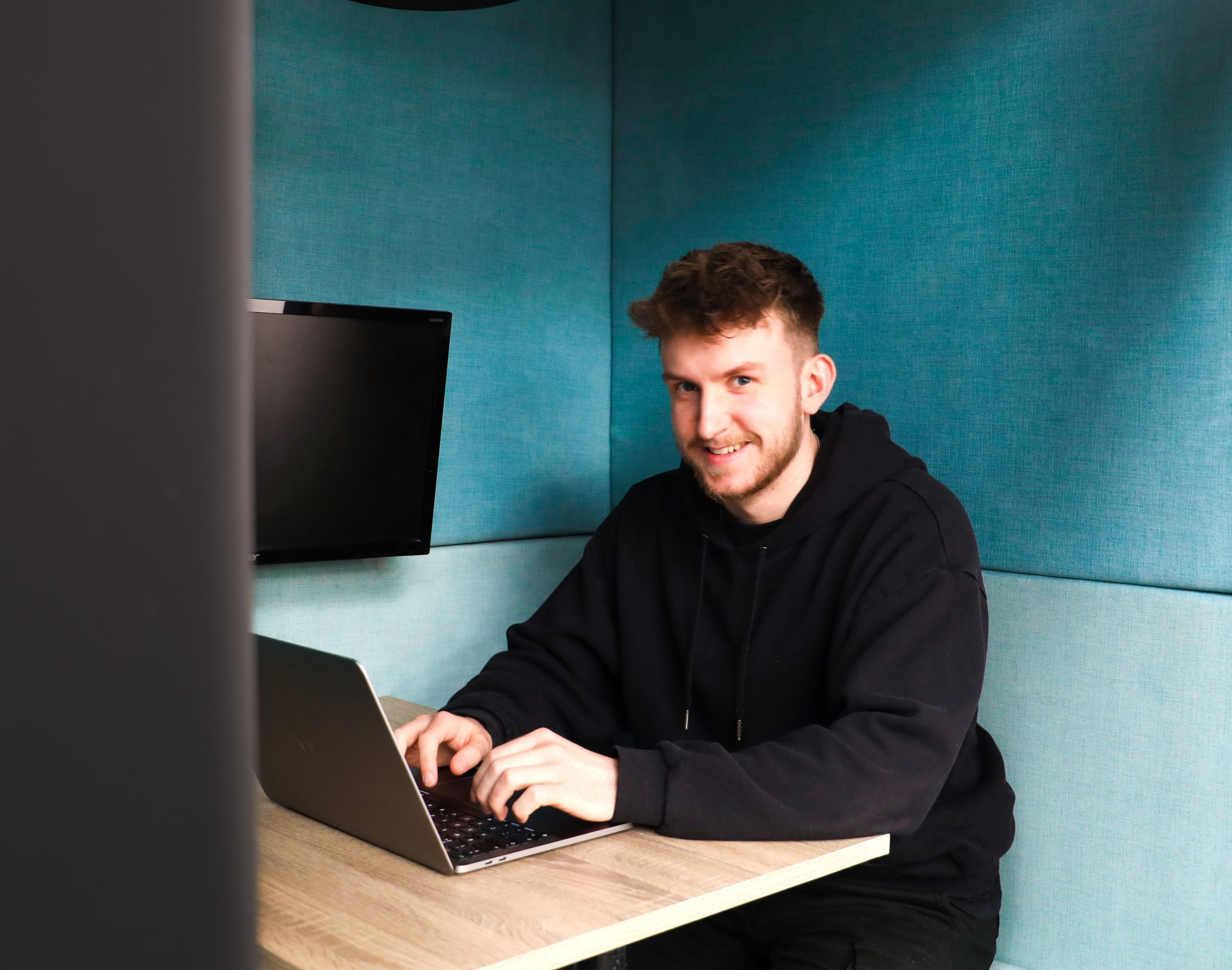 Harrison Lemon working from a mac laptop in a black hoodie